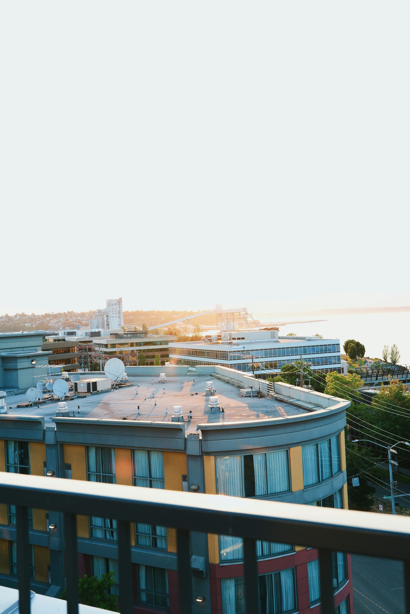 Modern city buildings overlooking water at bright sunset.