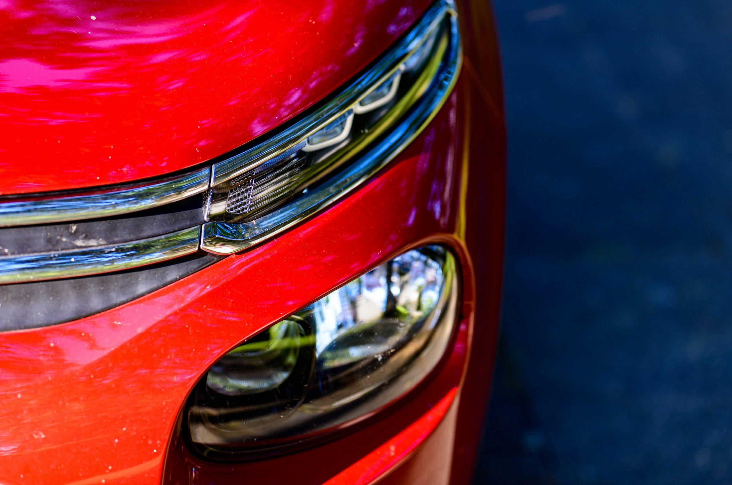 Modern red car's headlight and grille details.