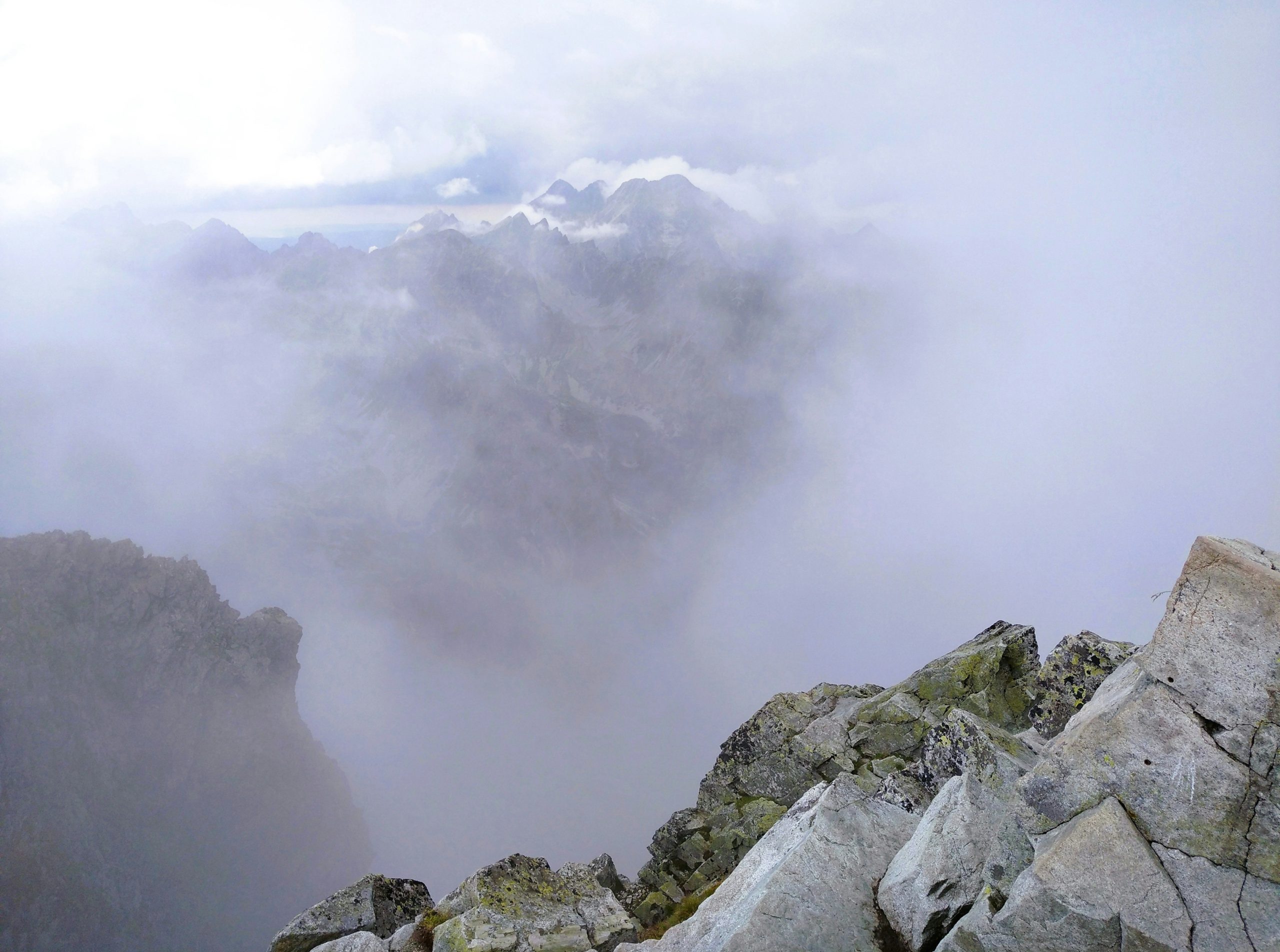 Rocky mountain peak shrouded in thick clouds and fog.