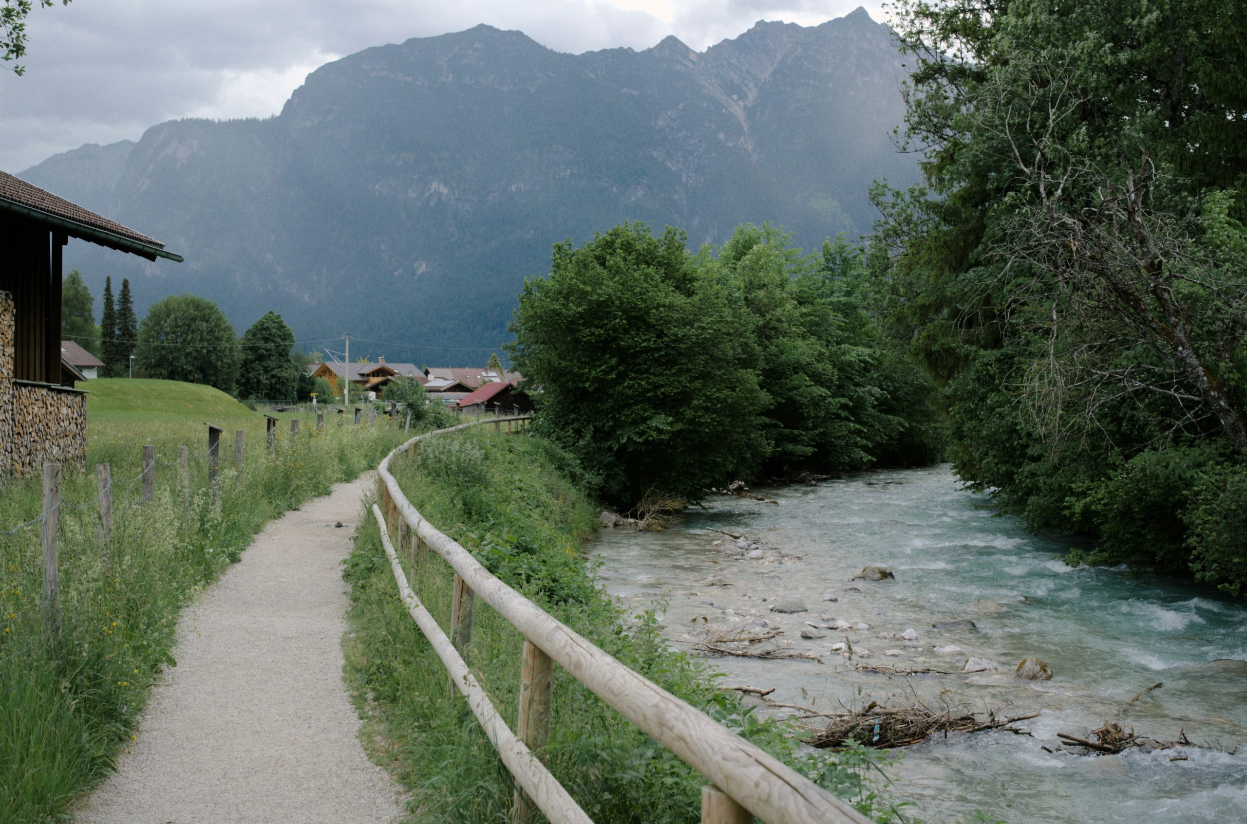 Scenic mountain path beside a river leading to a village.