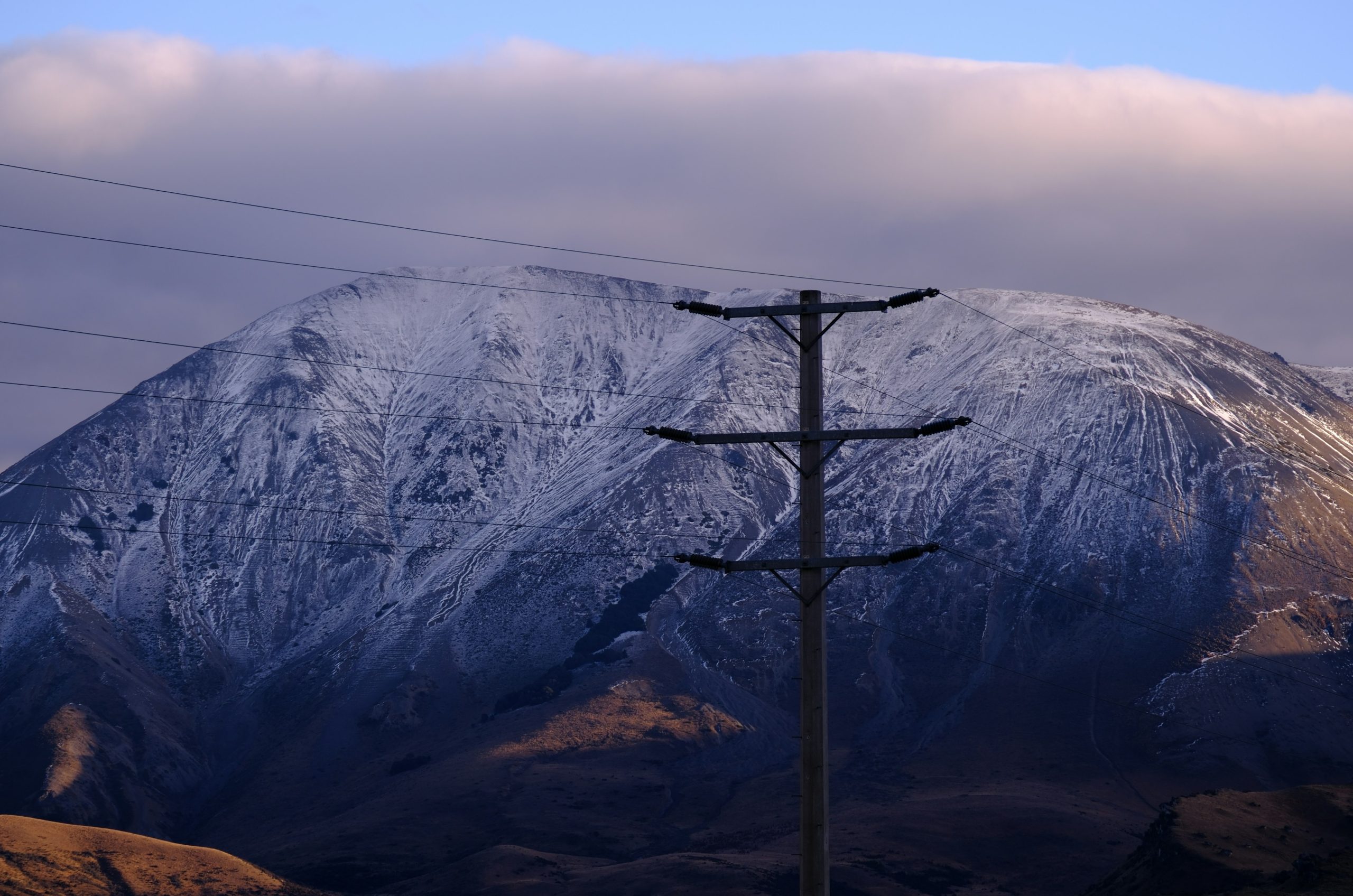 Utility pole in front of a snow-capped mountain.