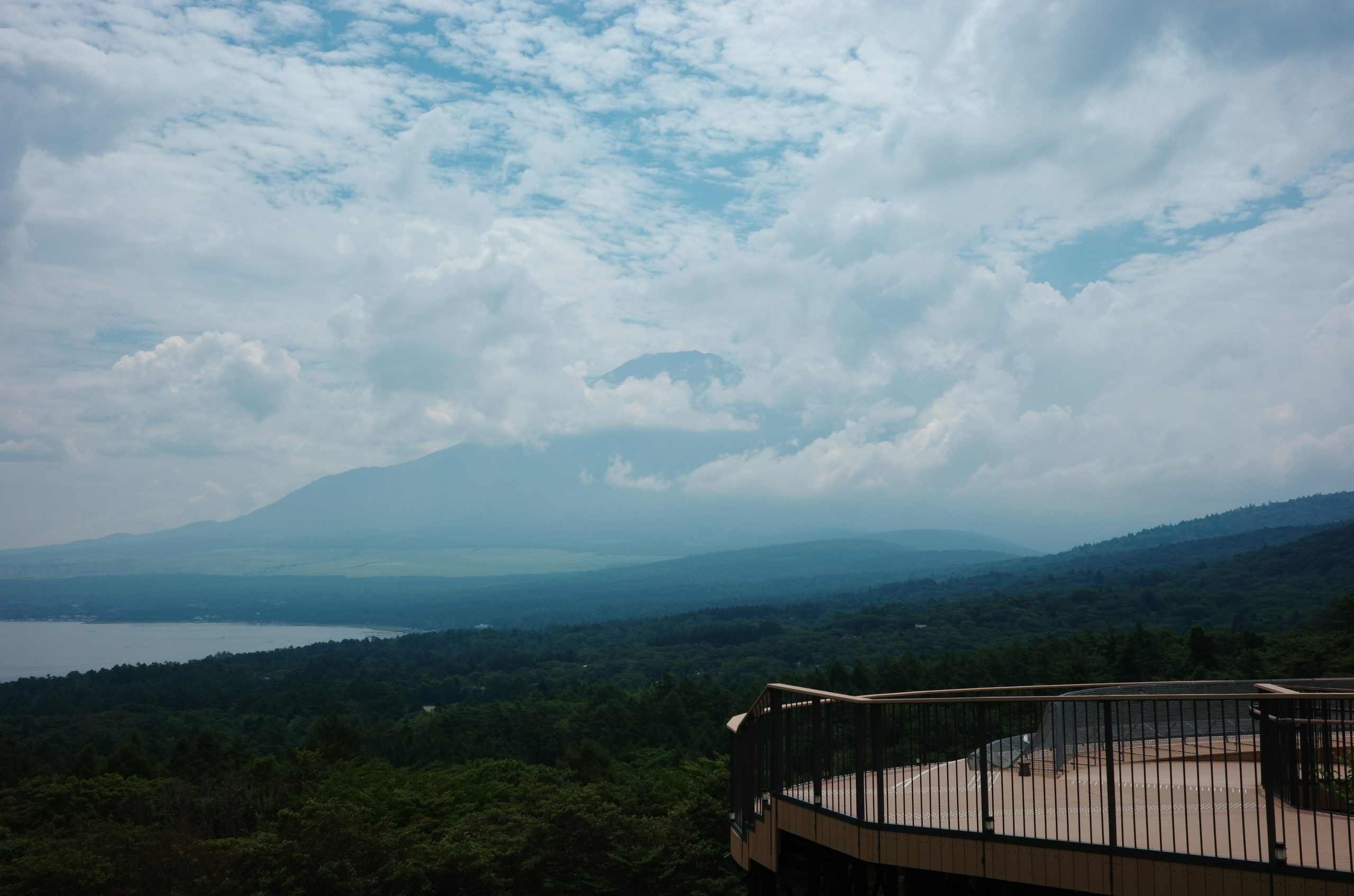 Viewing deck overlooking a lake, mountains, and cloudy sky.