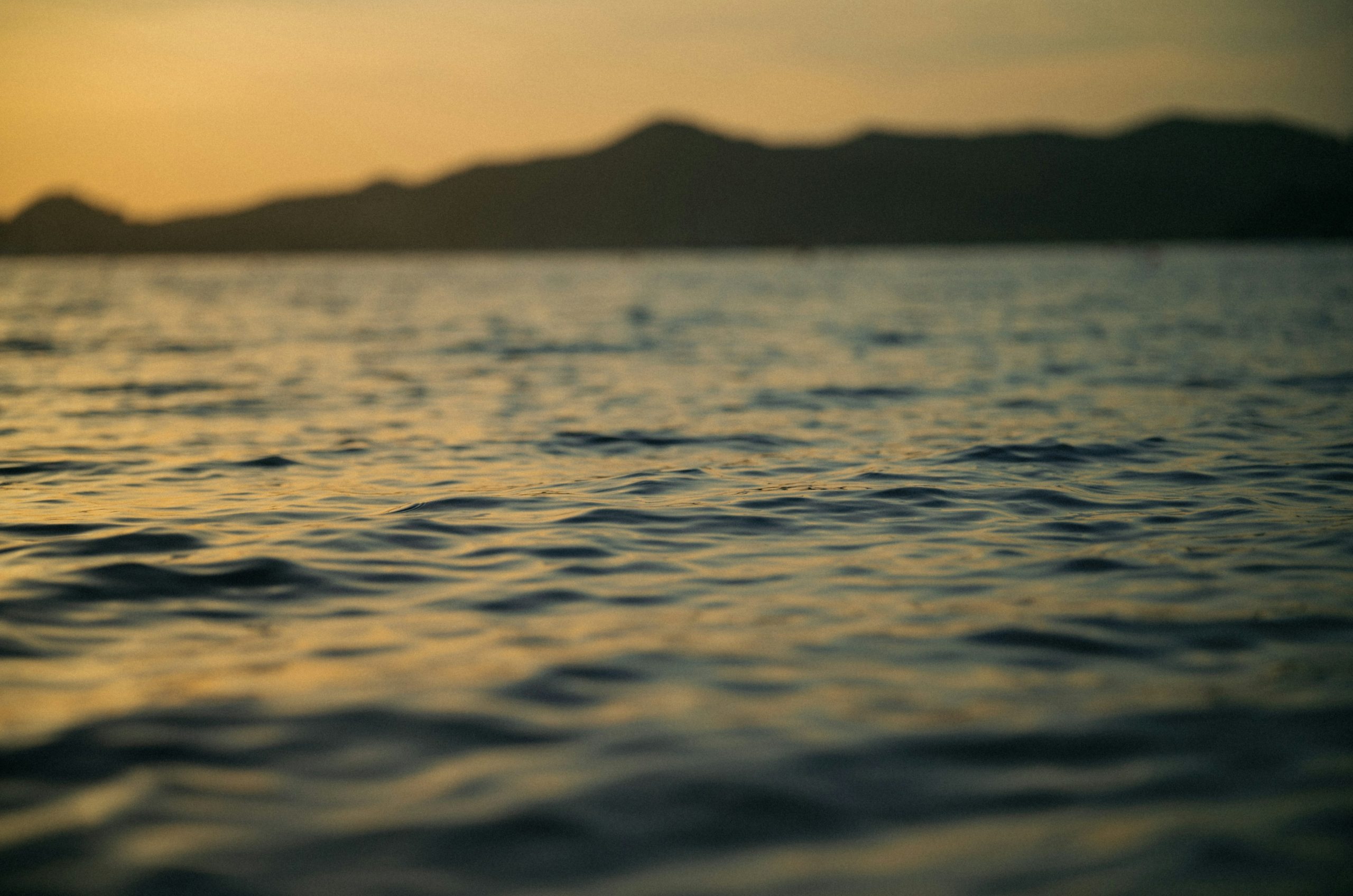 Water ripples with blurred mountains at sunset