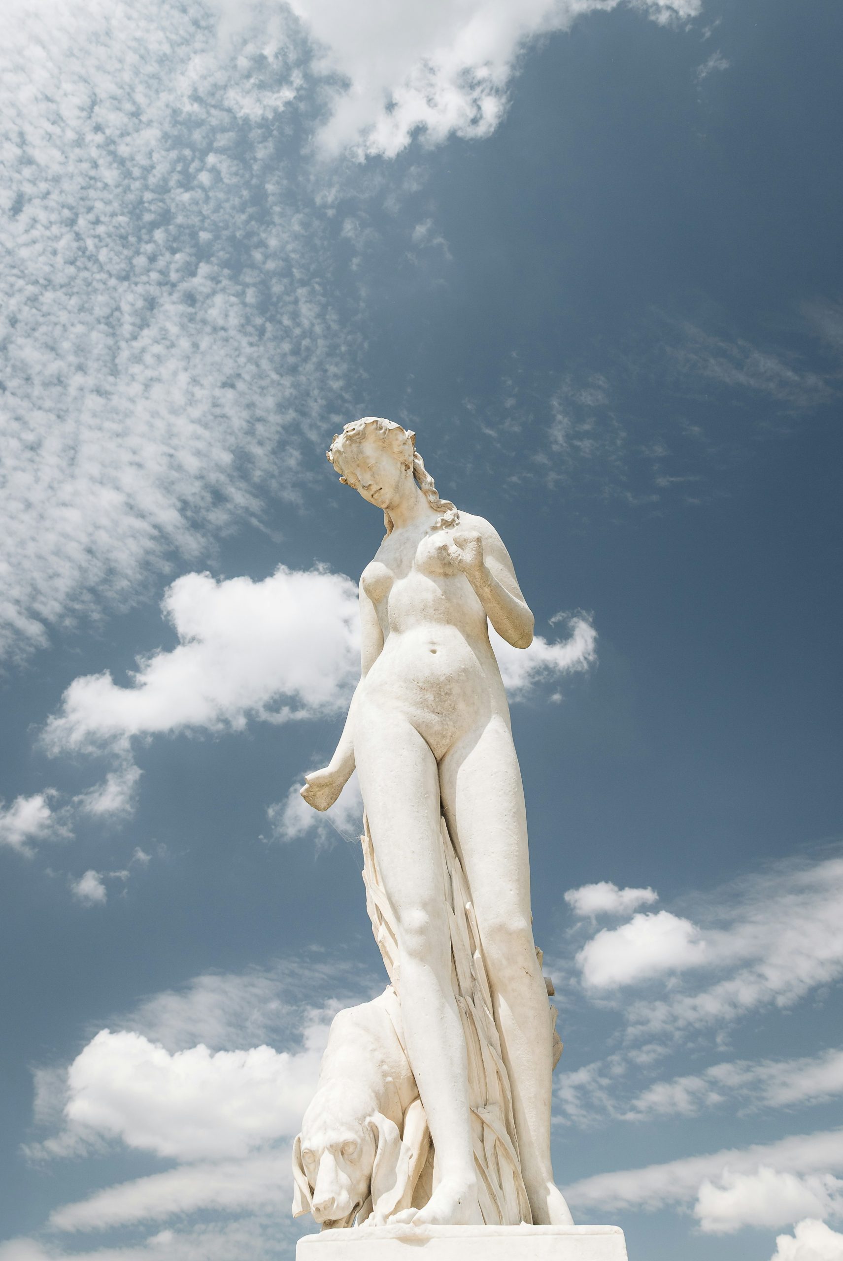 White marble statue against cloudy blue sky in paris
