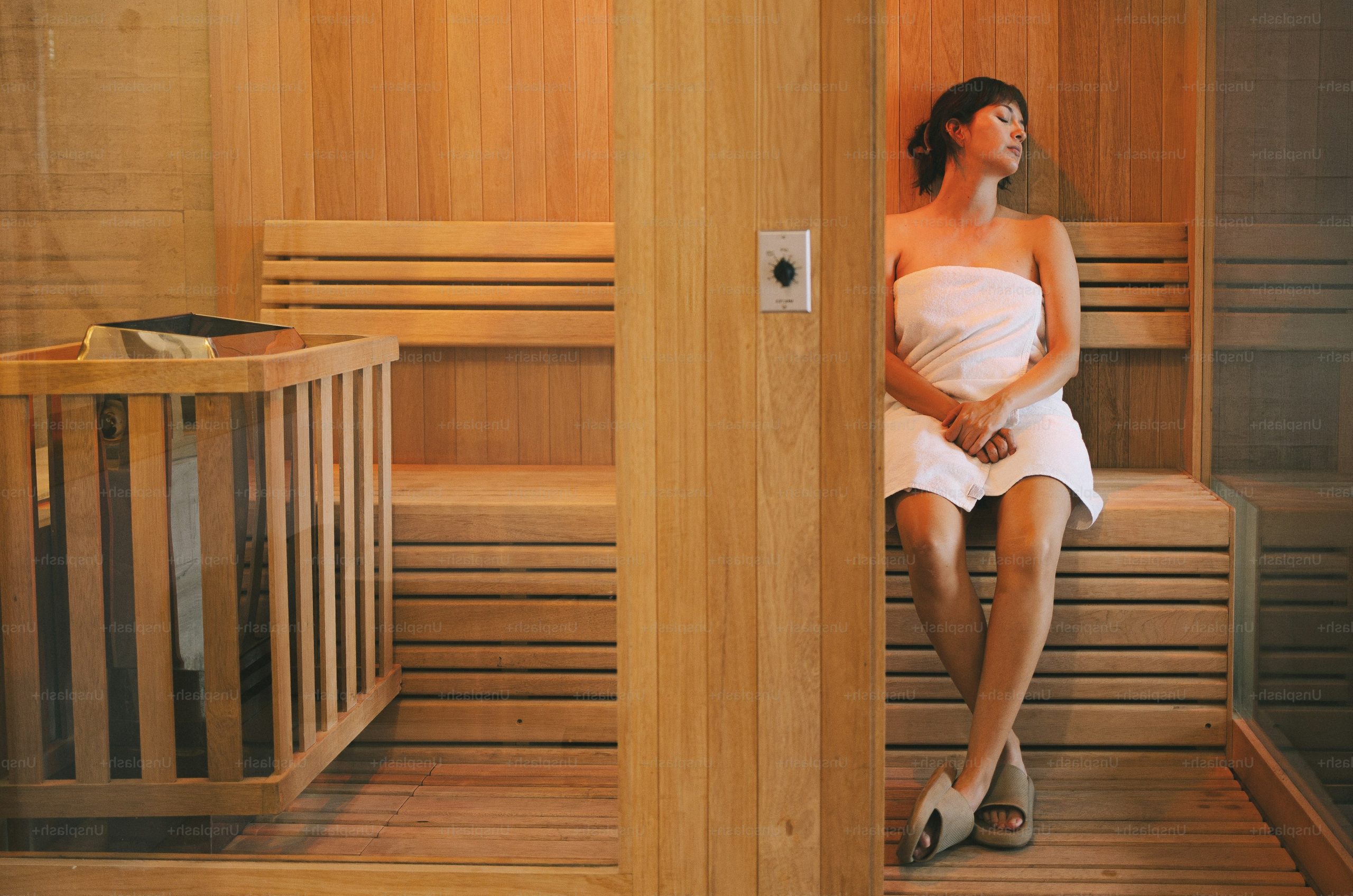 Woman in towel relaxing in wooden sauna