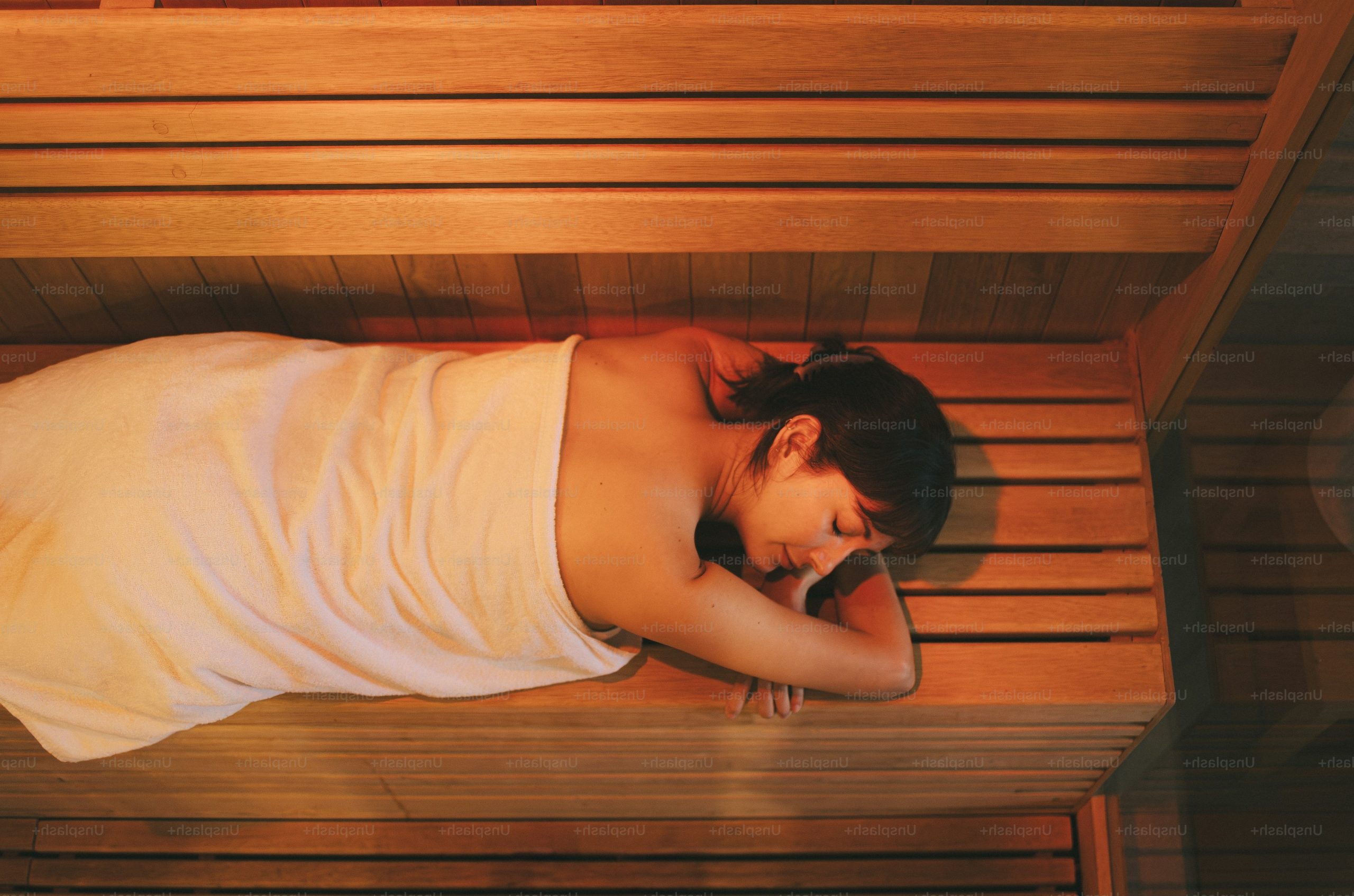 Woman unwinding on a wooden sauna bench