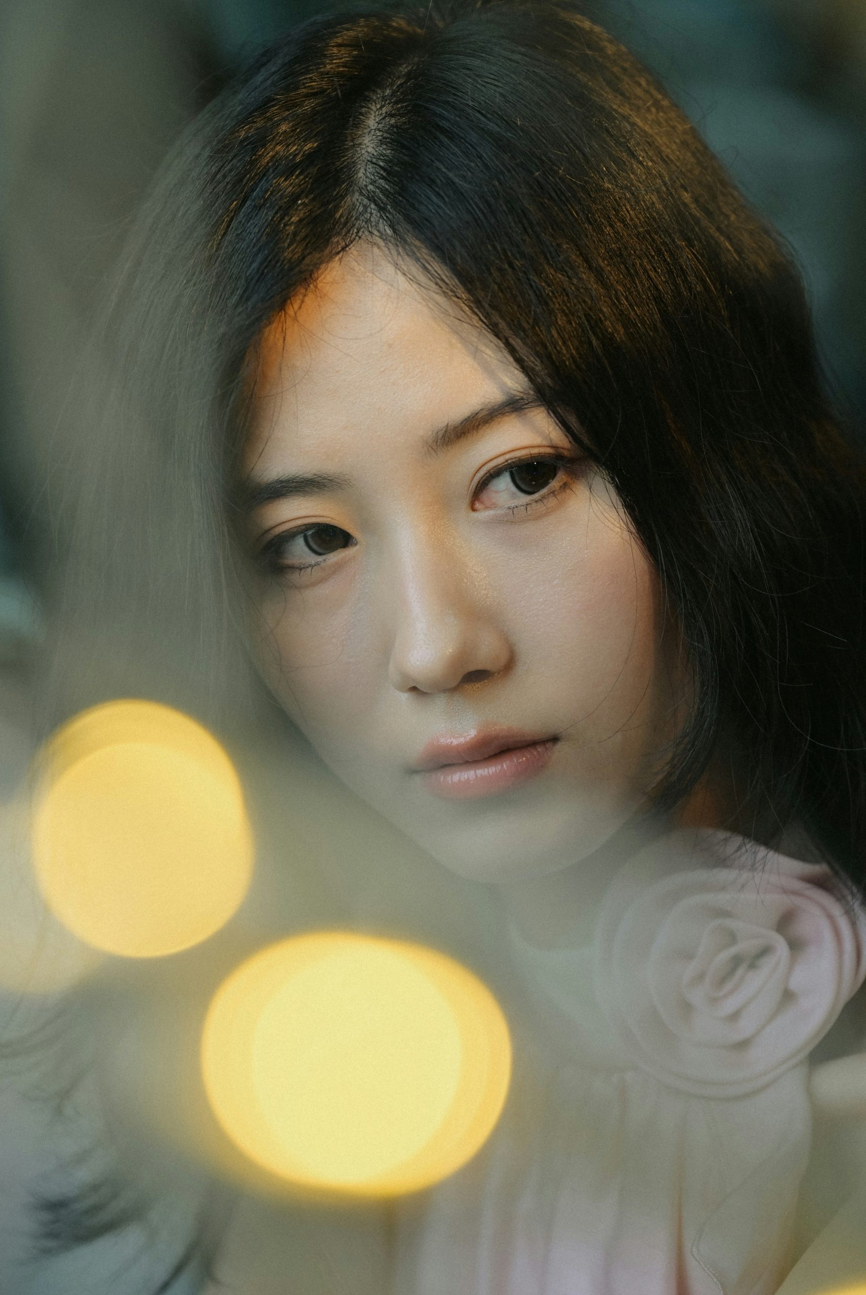 Young asian woman looking through soft, blurry lights.