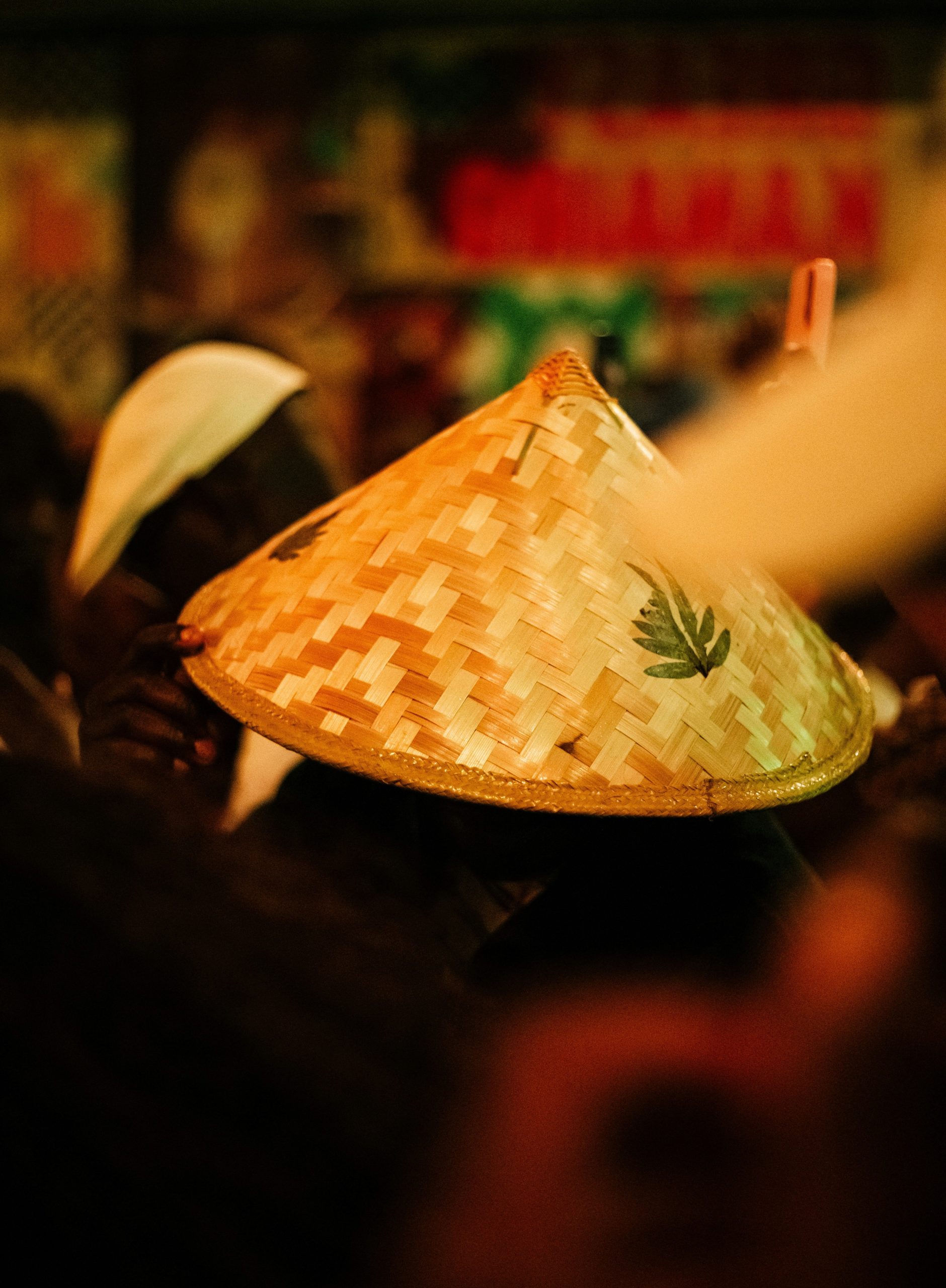 A conical straw hat with a green leaf design.