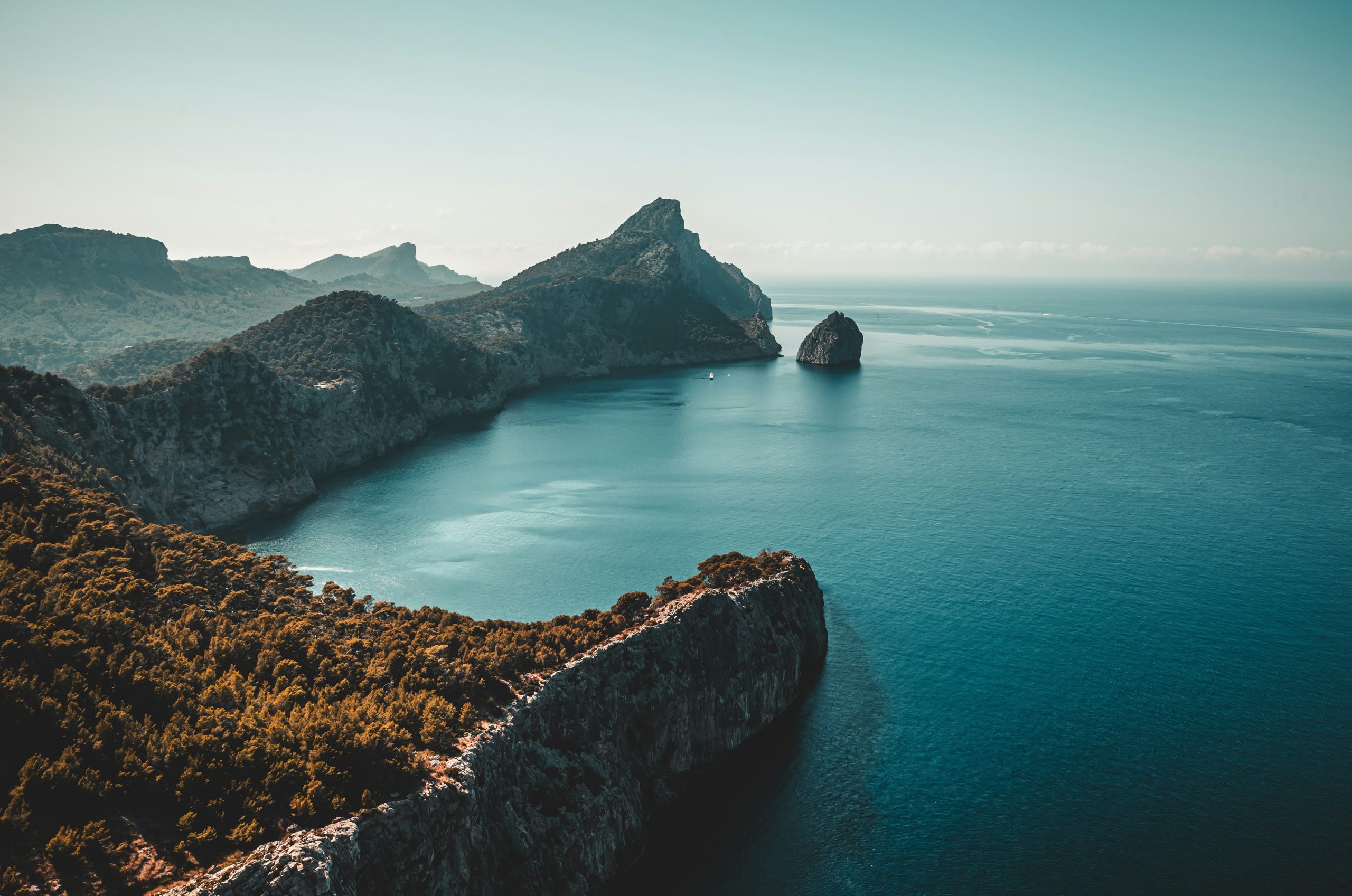 Majestic cliffs and mountains meet the calm blue ocean.