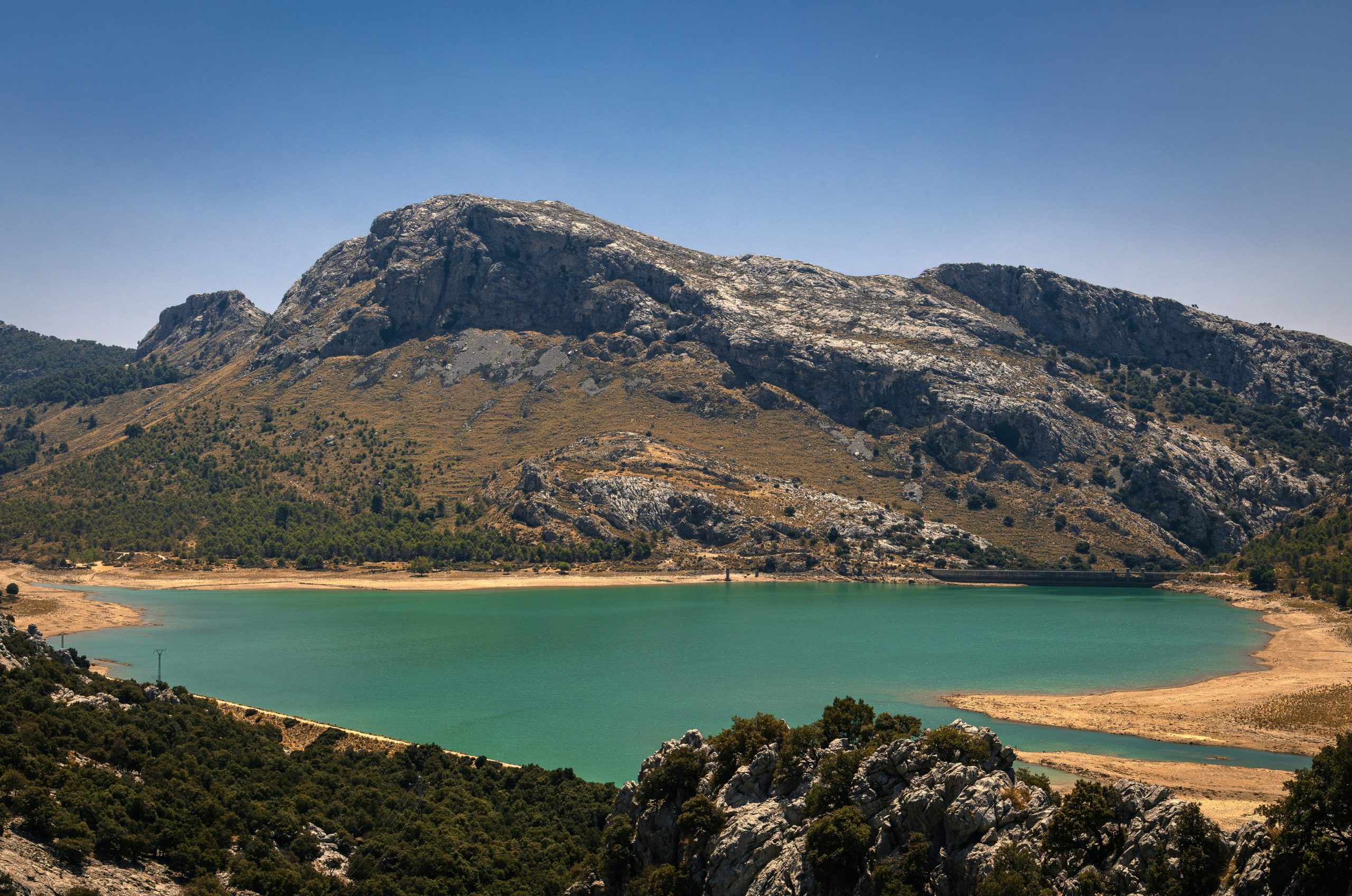 Turquoise lake with rocky mountains under a clear blue sky.