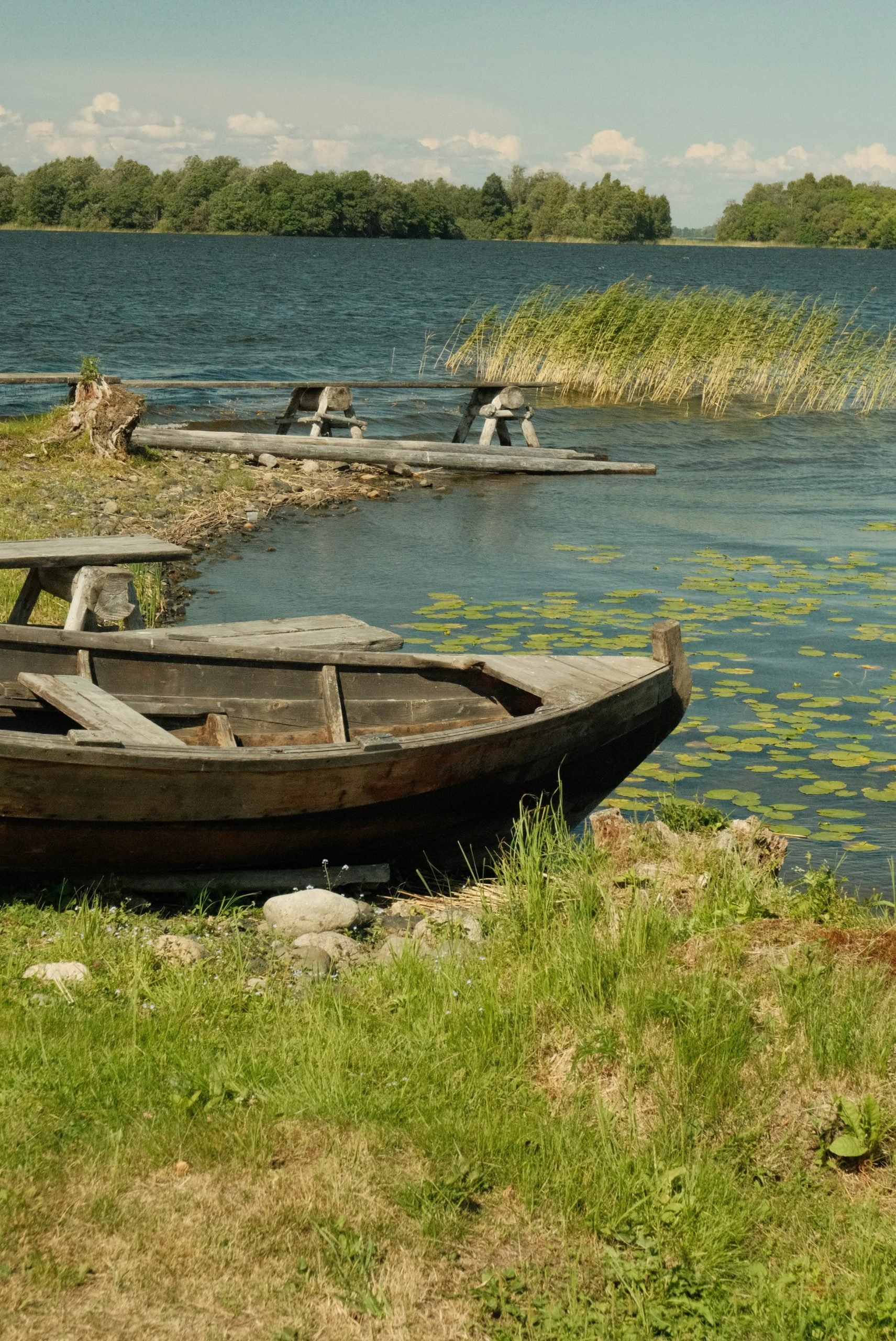 Old wooden boat by a lake with reeds and islands.