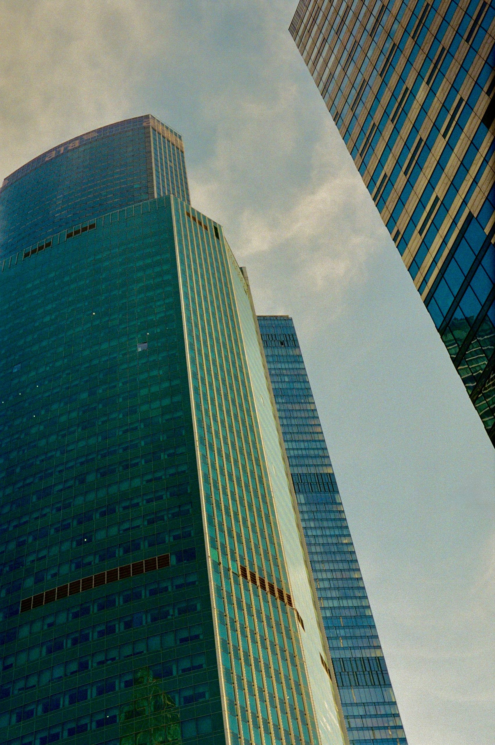 Modern glass skyscrapers reaching towards a cloudy sky.