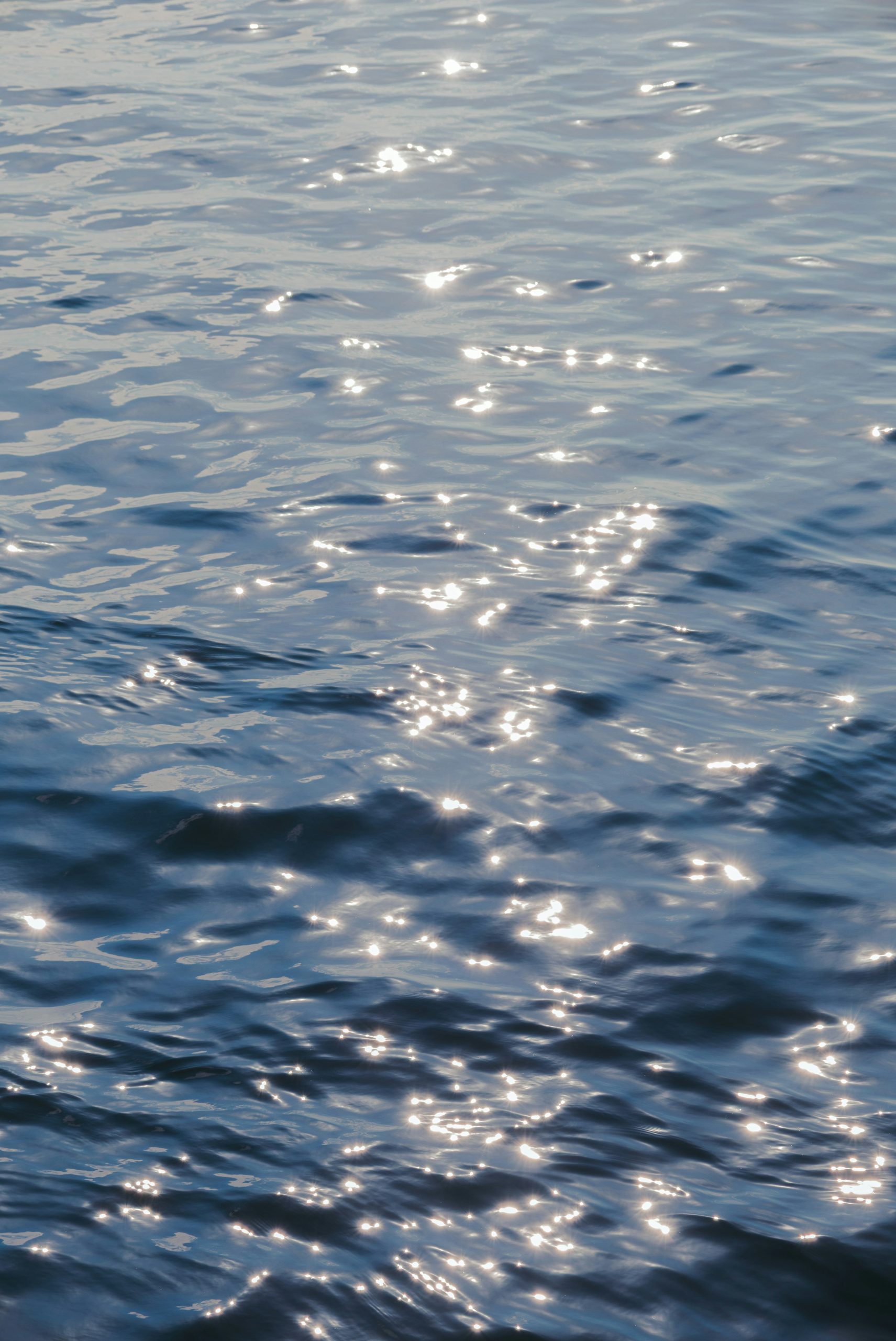 Sunlight sparkling on blue rippling water.