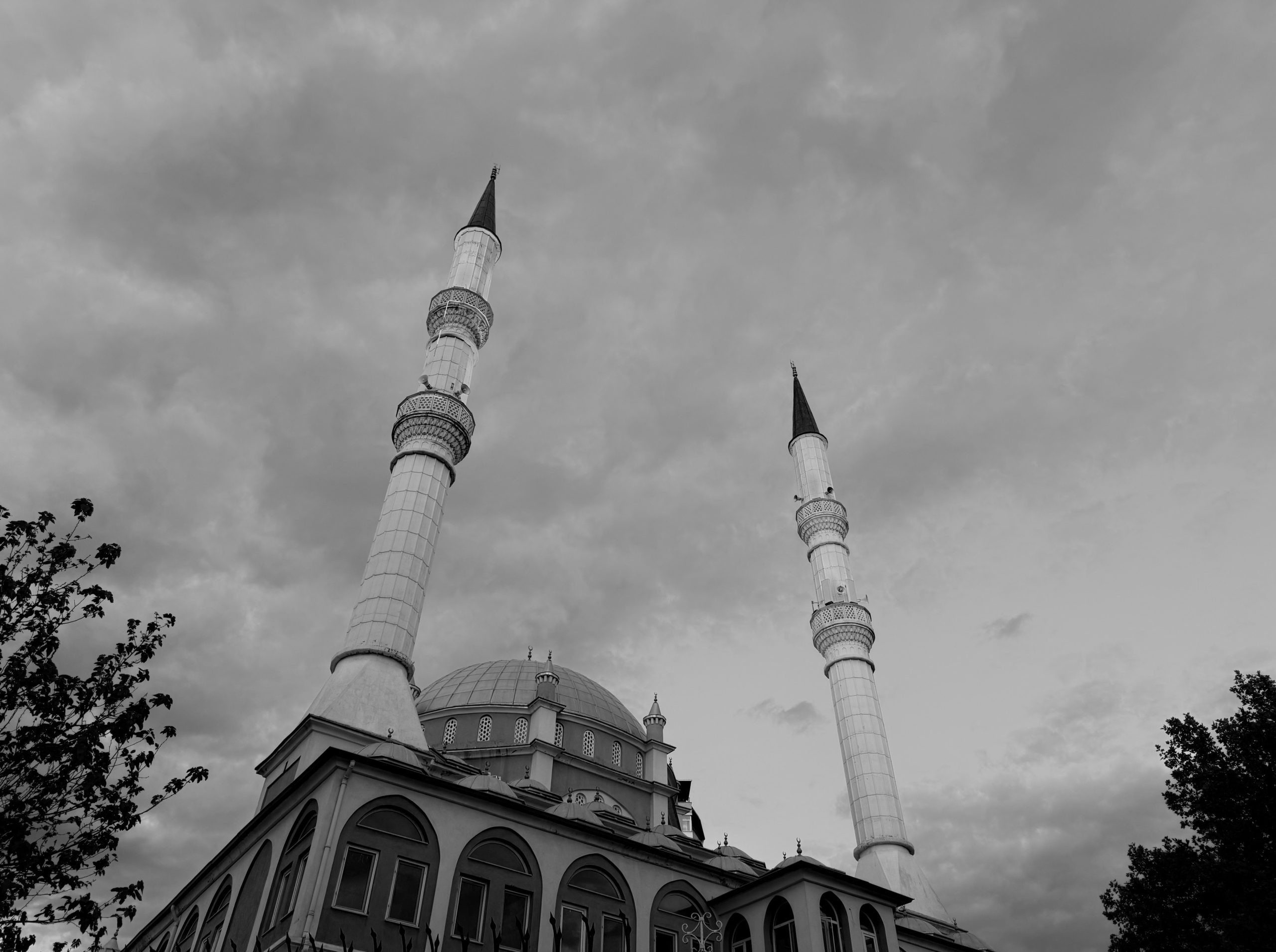 Mosque with two tall minarets against a cloudy sky.