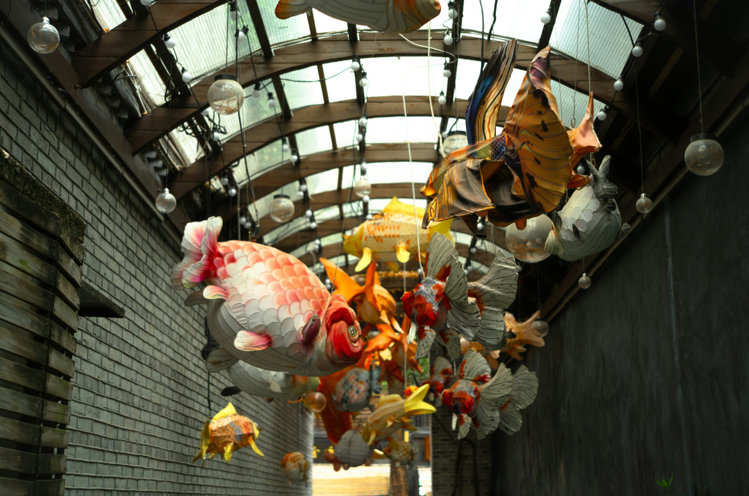 Colorful fish lanterns hang from a curved ceiling walkway.