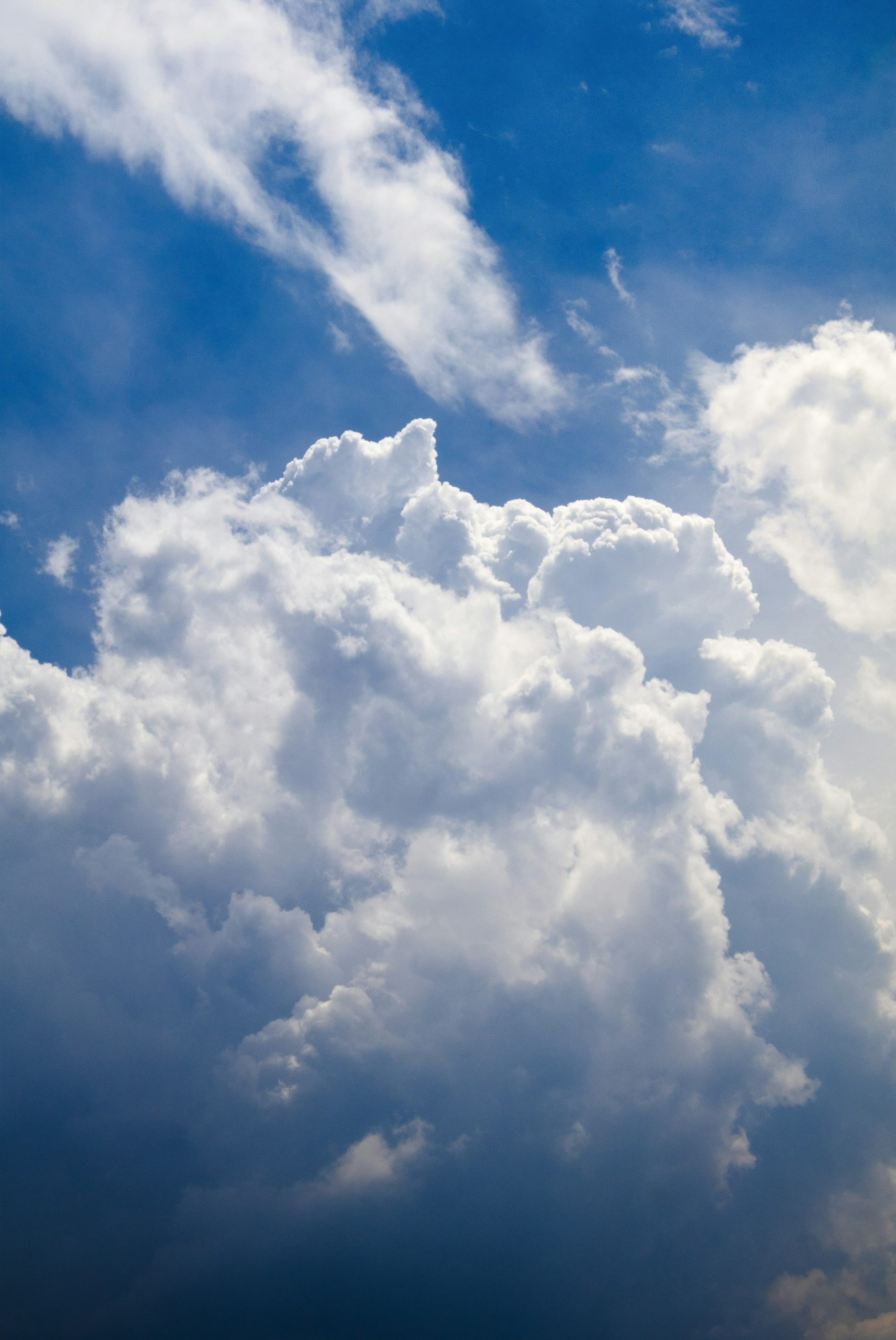 Fluffy white cumulus clouds drifting across a bright blue sky.