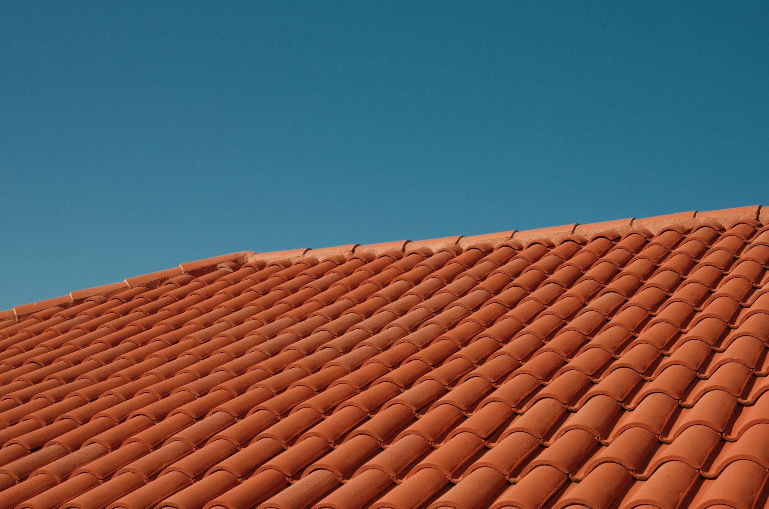 Red clay roof tiles against a clear blue sky.