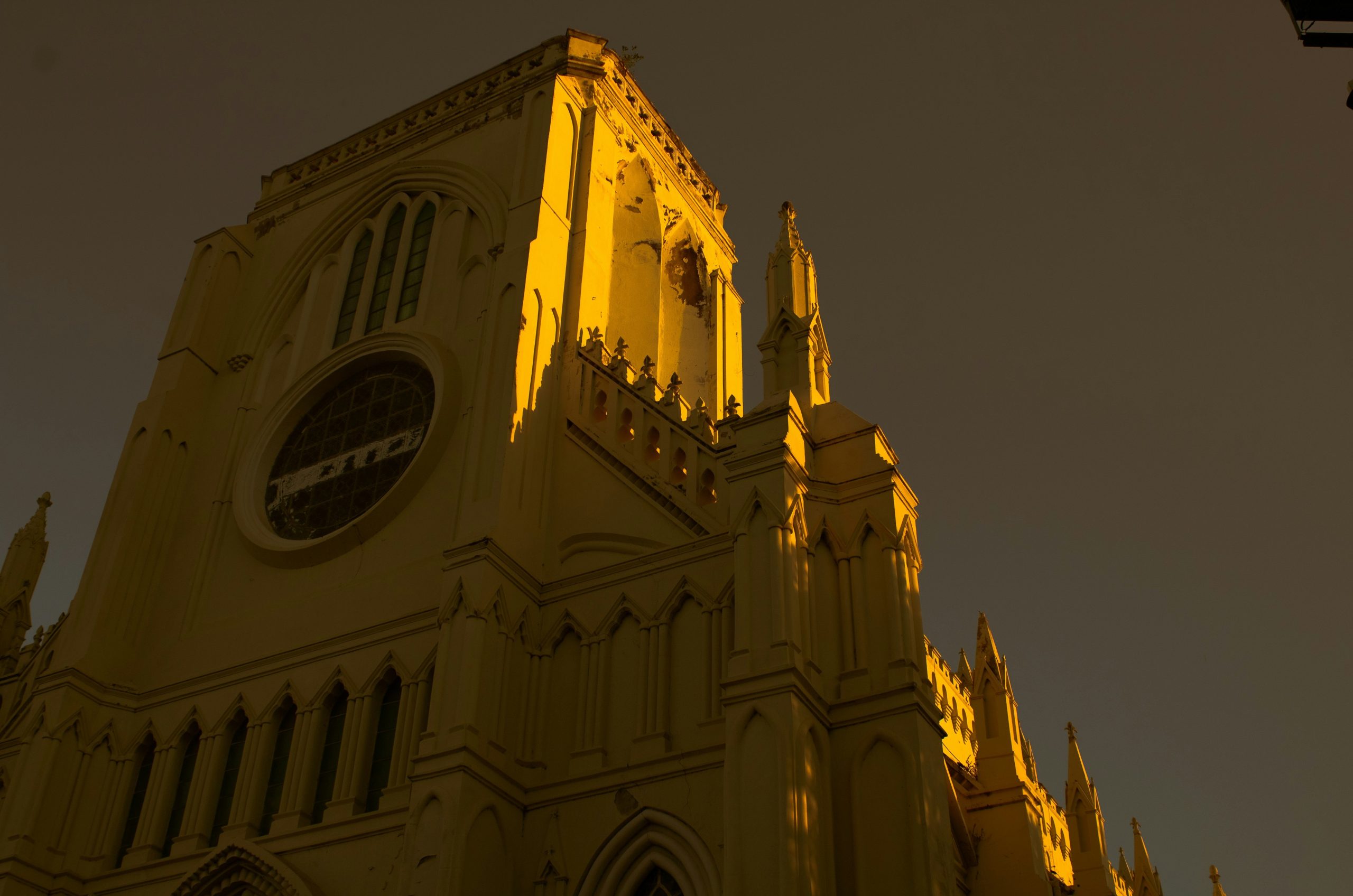 A gothic church tower illuminated by warm golden light against a dark sky.