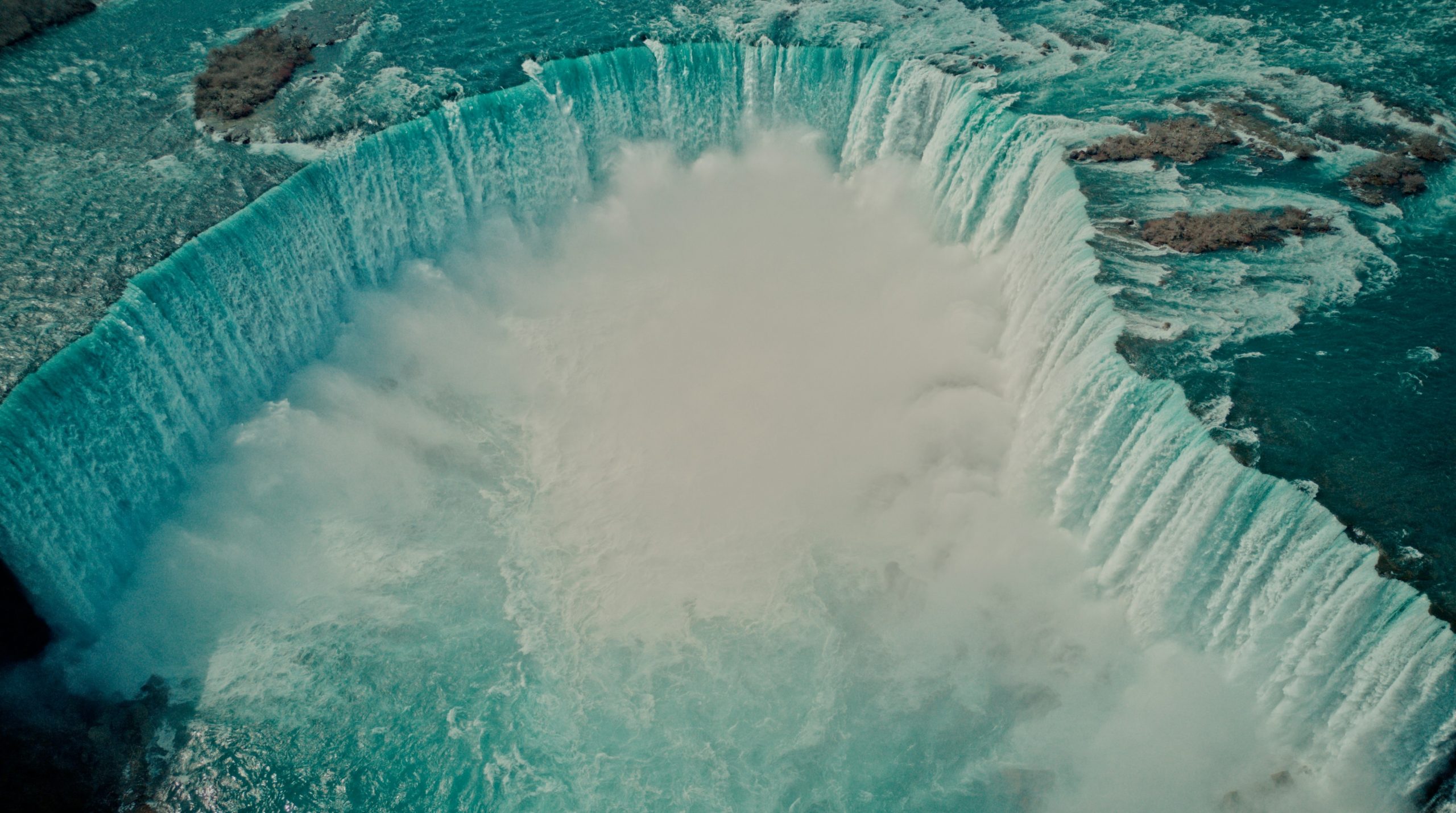 An aerial view of the Horseshoe Falls at Niagara Falls with mist rising.