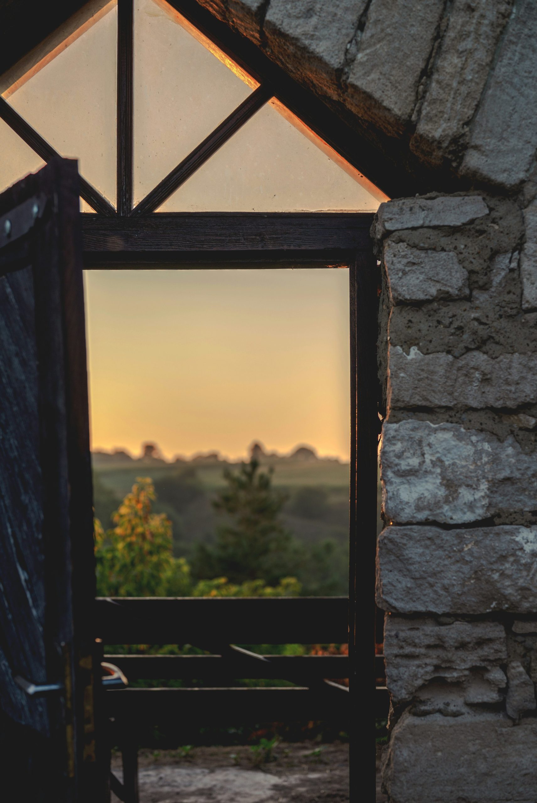 A view of a rural landscape through an open stone doorway at golden hour.
