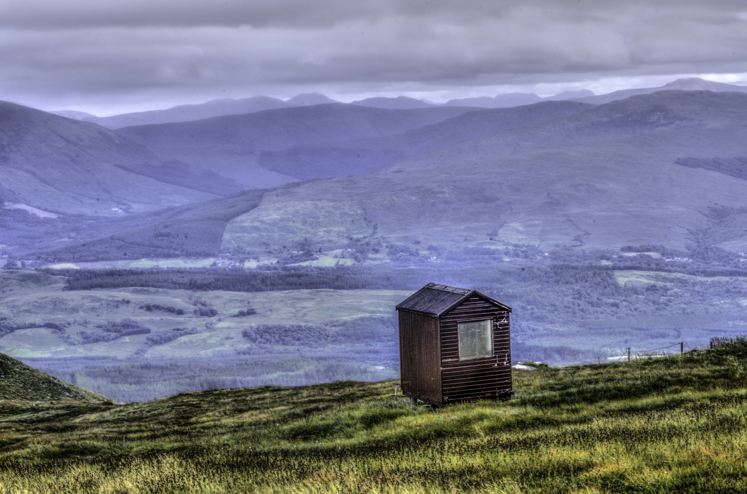 brown wooden house on green grass field near body of water during daytime