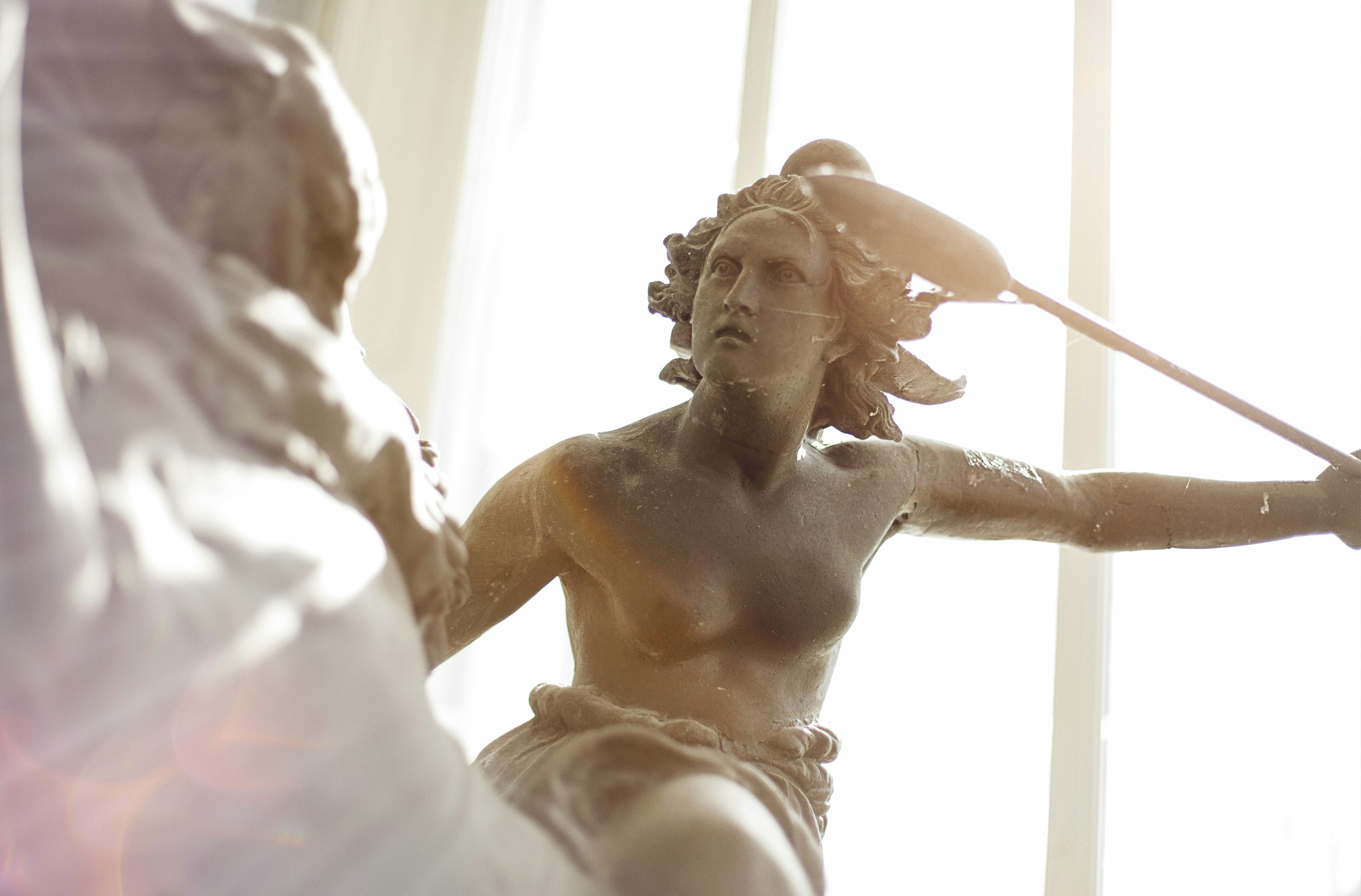 man in white shirt holding a stick statue