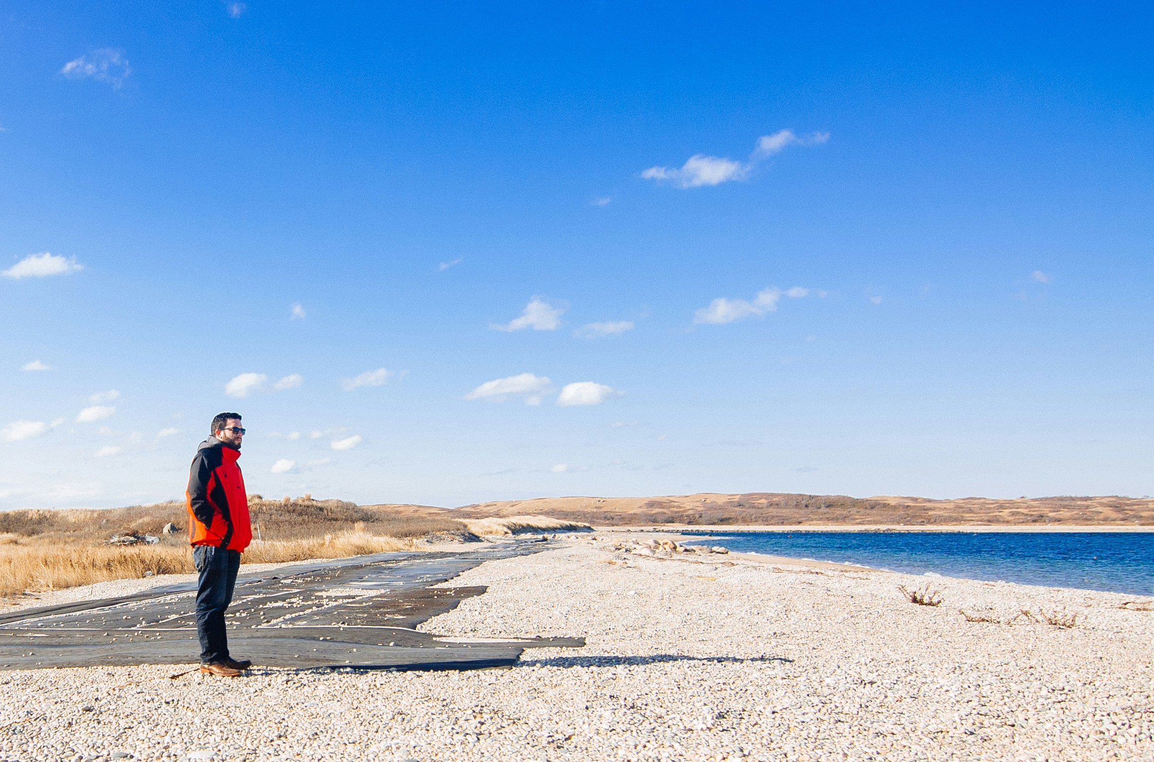 man in black jacket standing on brown sand under blue sky during daytime