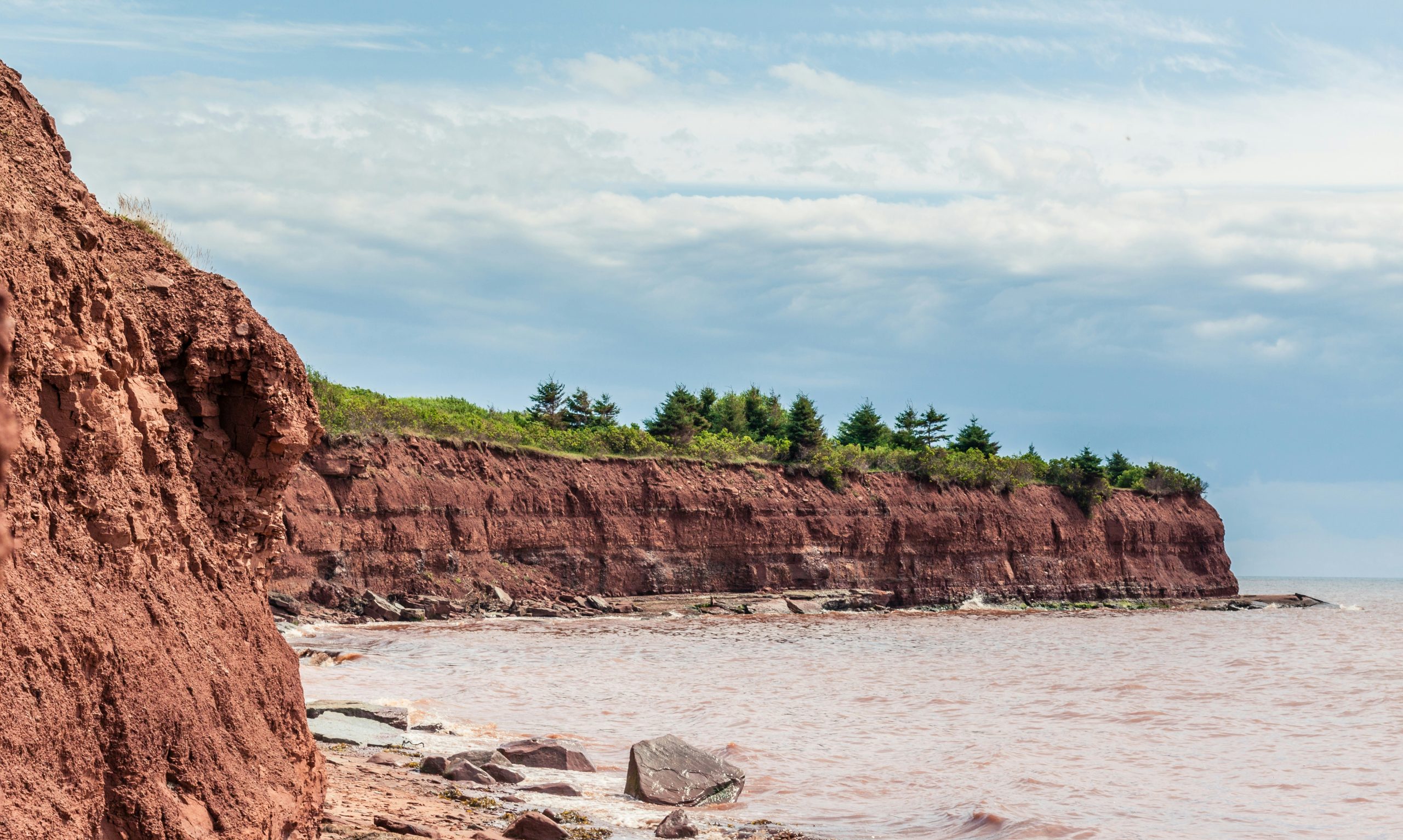 brown rocky mountain beside body of water during daytime