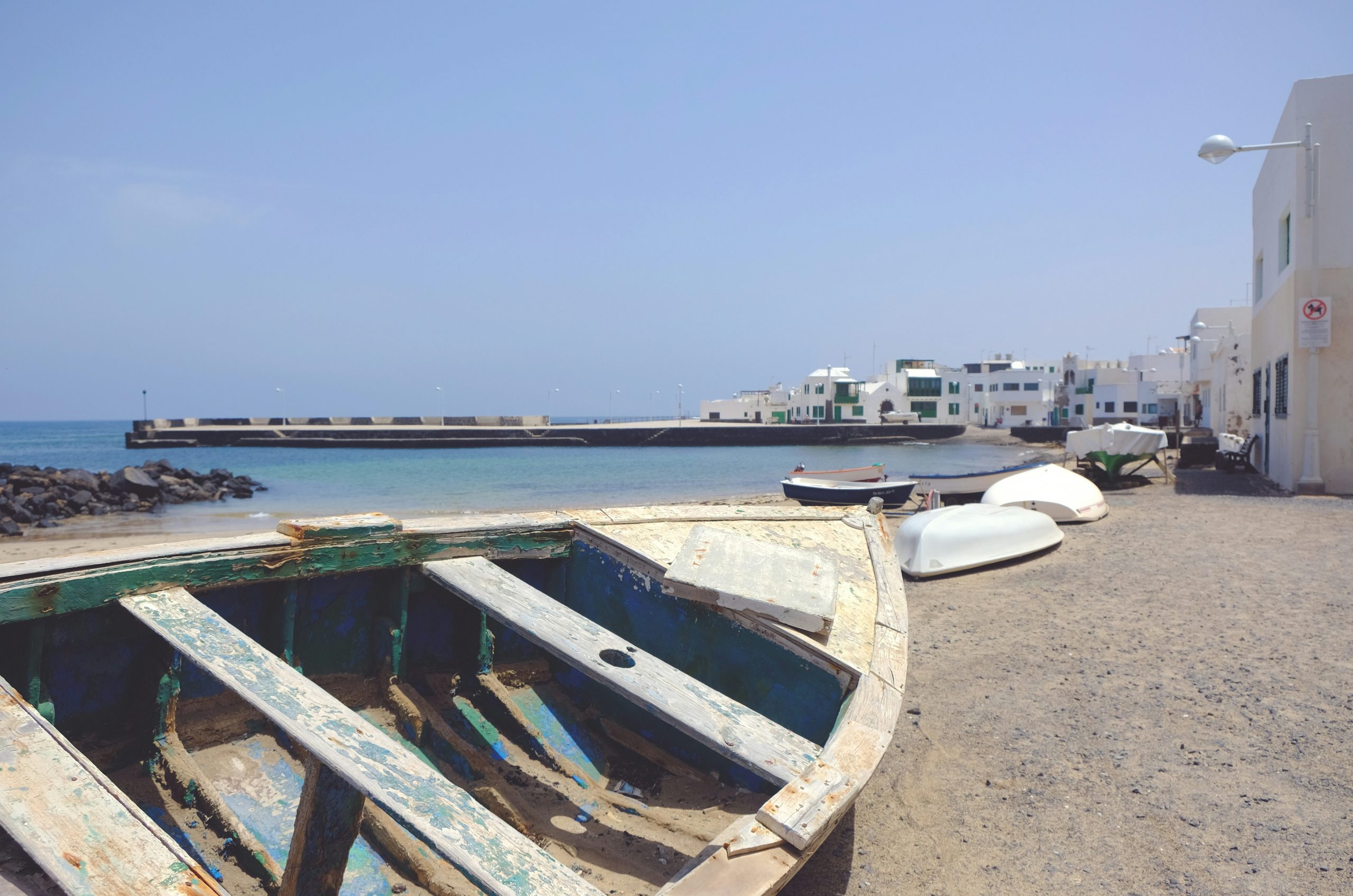 white and blue boat on beach during daytime