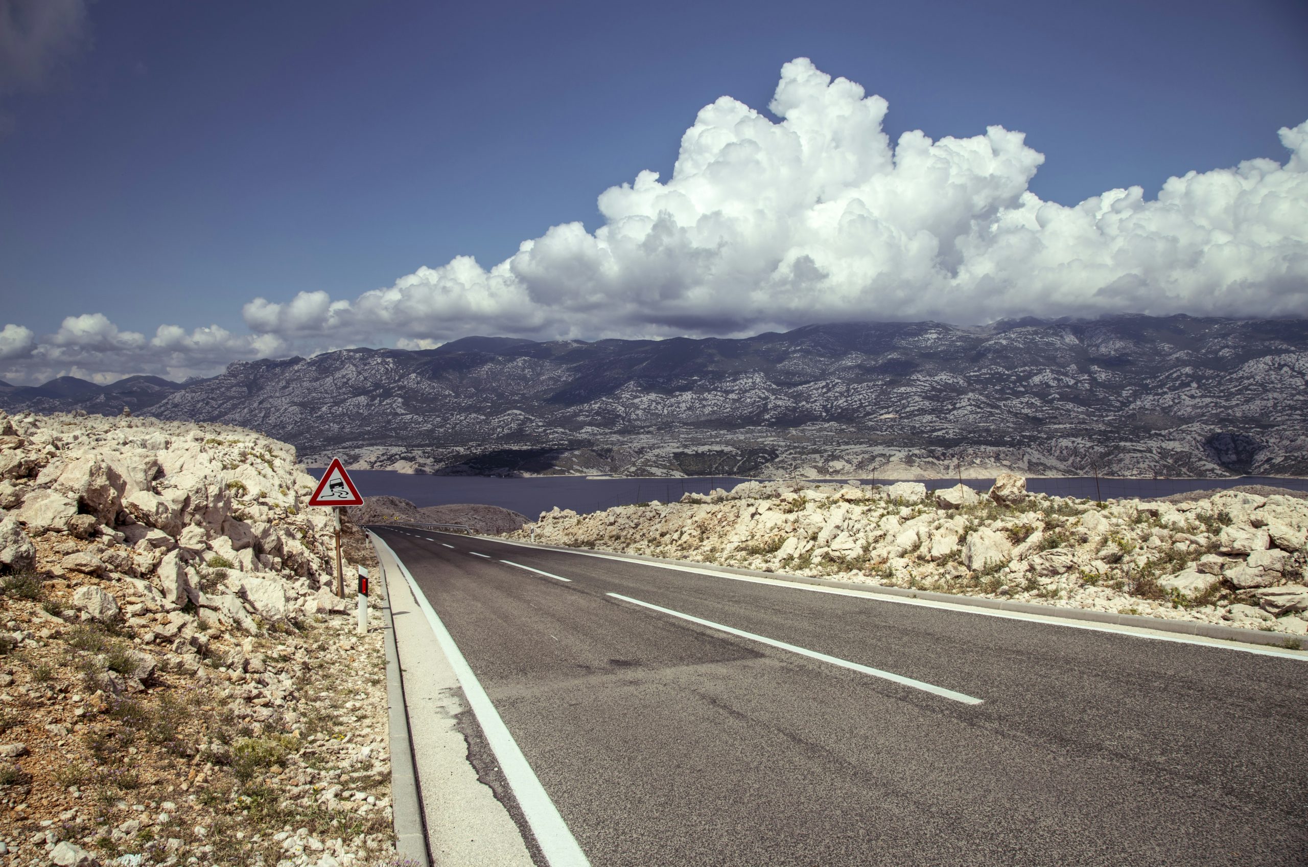 gray asphalt road under white clouds and blue sky during daytime