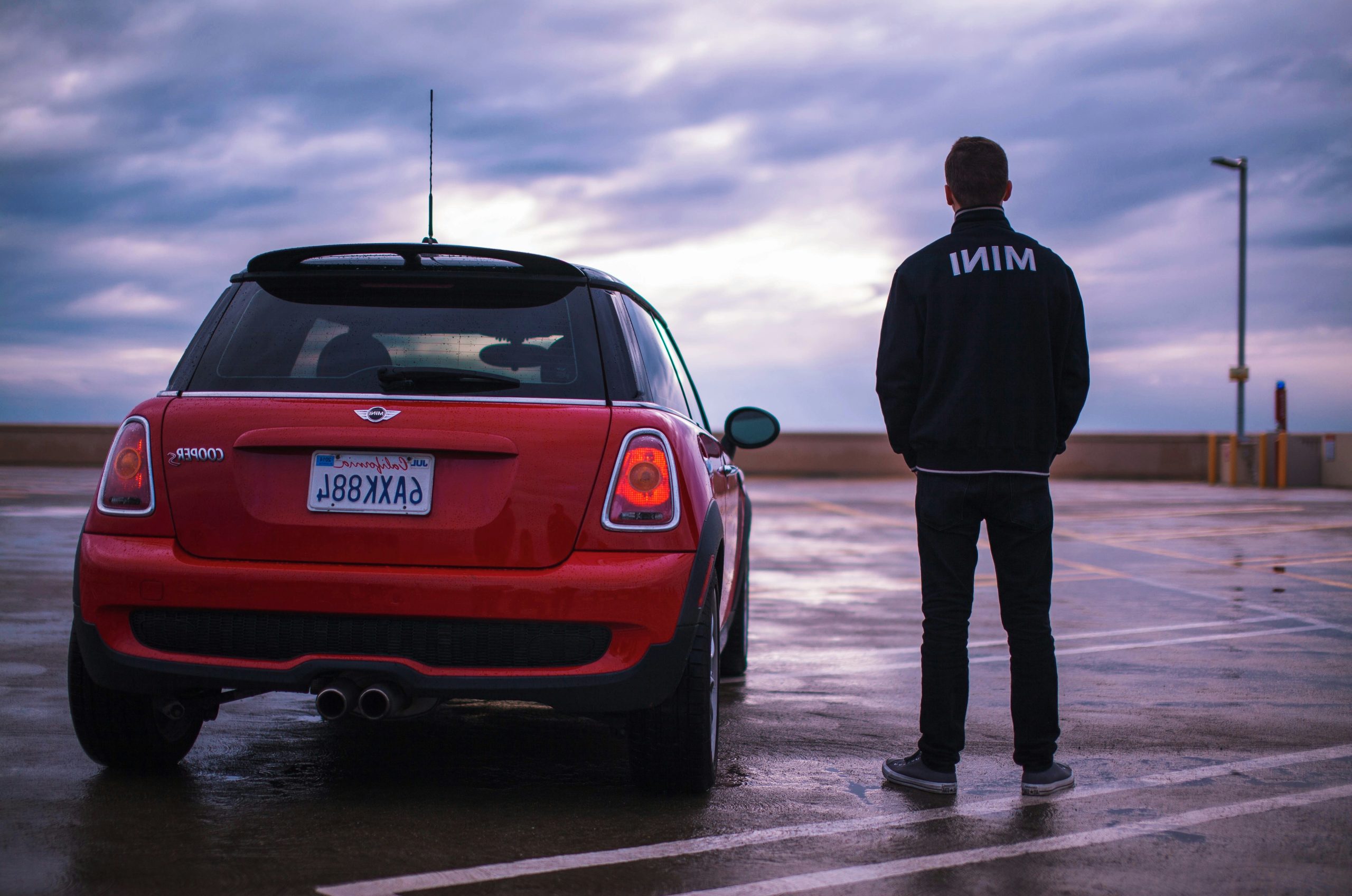 man standing red Mini vehicle during daytime