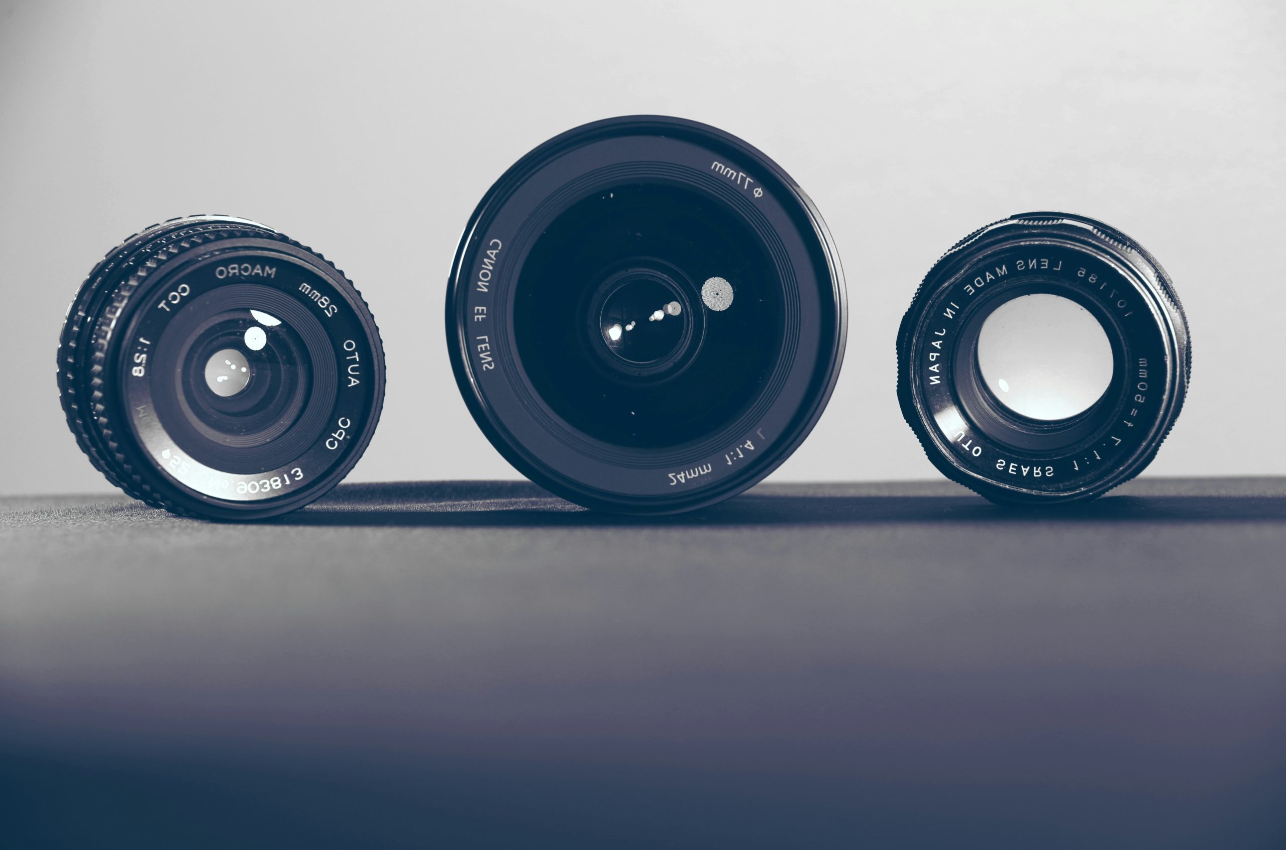 three black camera lenses on gray surface