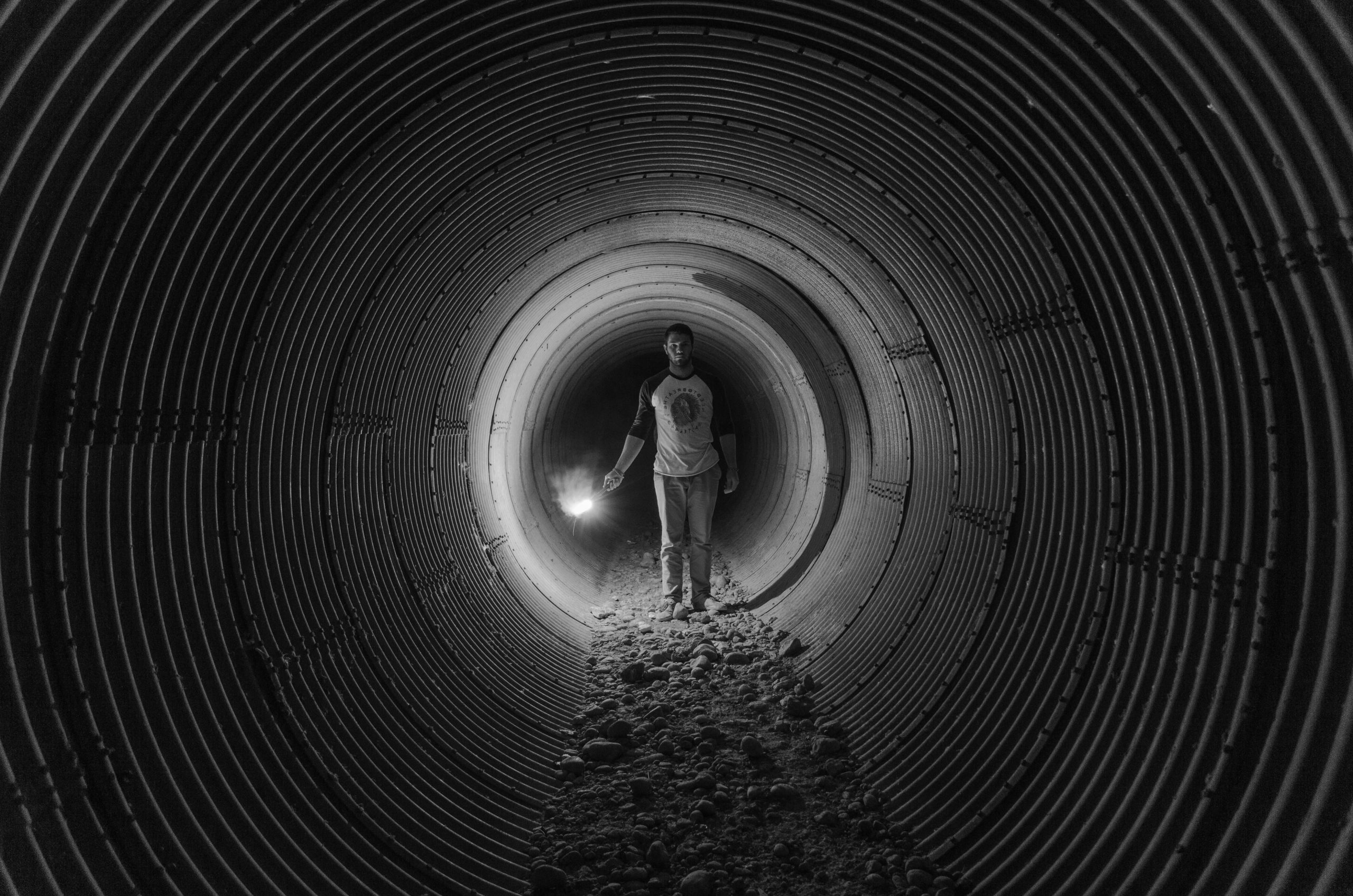 grayscale photography of person walking on tunnel