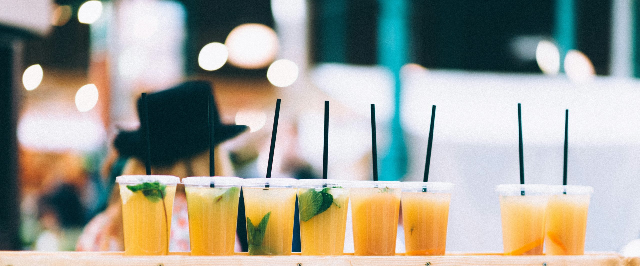 eight cups of yellow drink with straw