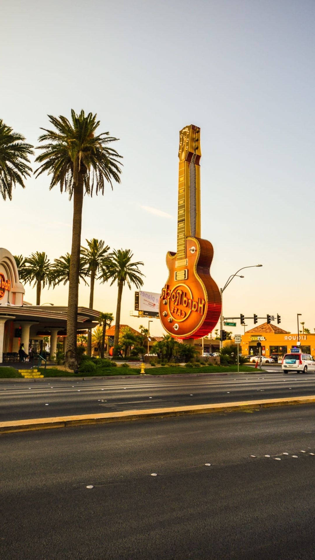 Giant guitar sign on desert highway with palm trees at sunset – Ultra HD Wallpaper